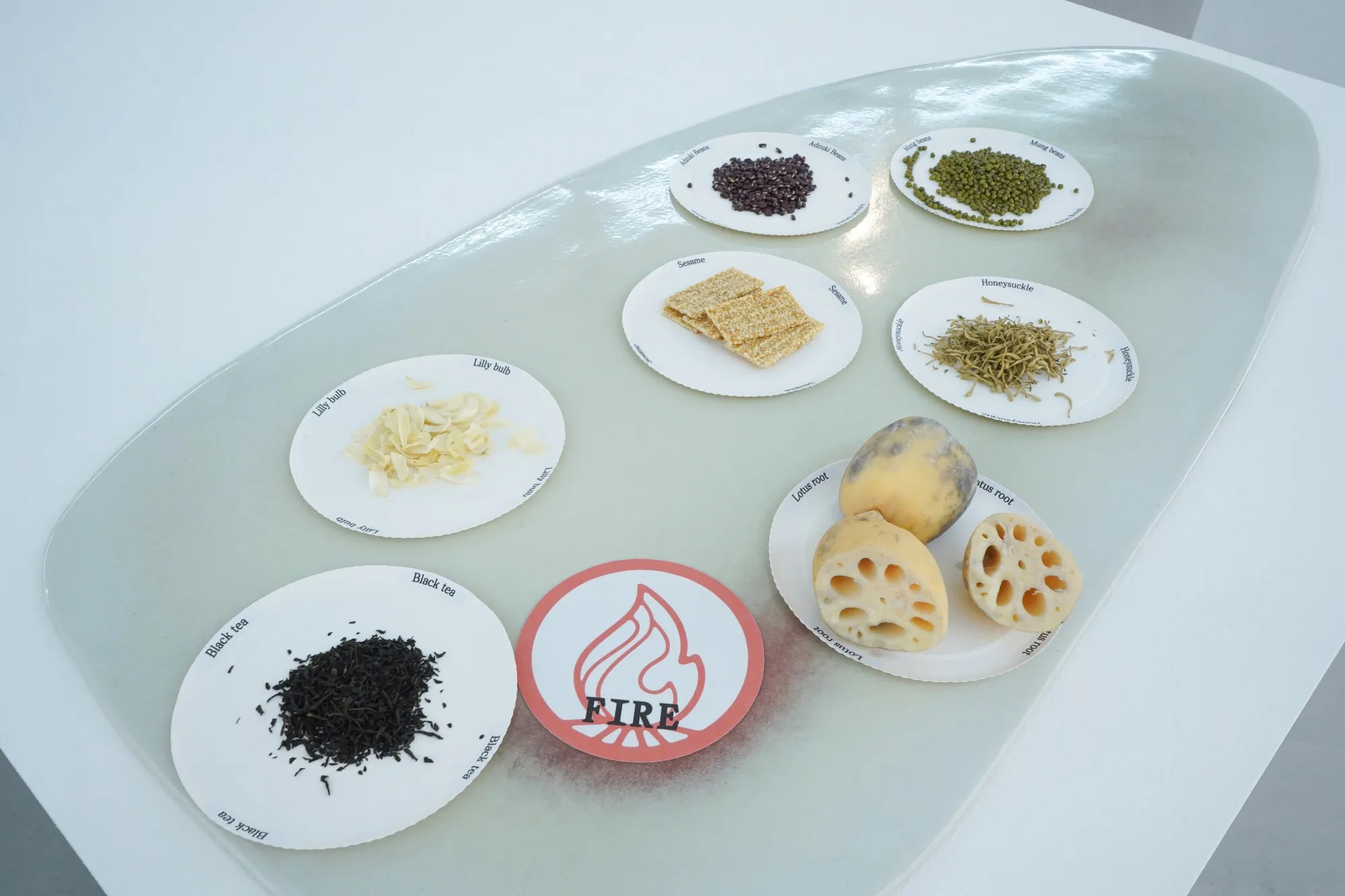 Bord van het element Vuur met zwarte thee, lelieknol, sesam, kamperfoelie, mungbonen, adzukibonen en lotuswortel