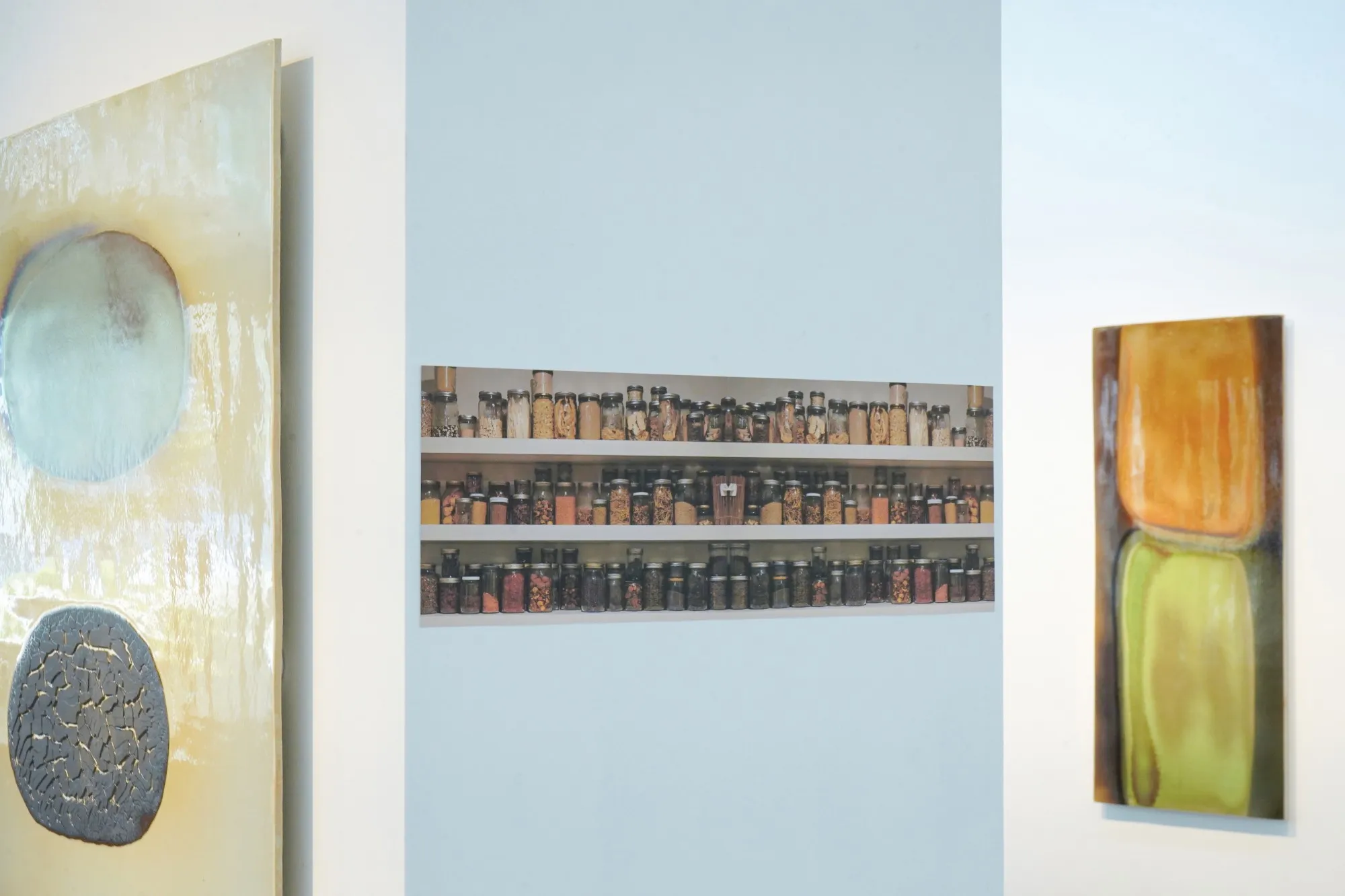 Expositiemuur met een print van planken vol potten met Chinese kruiden